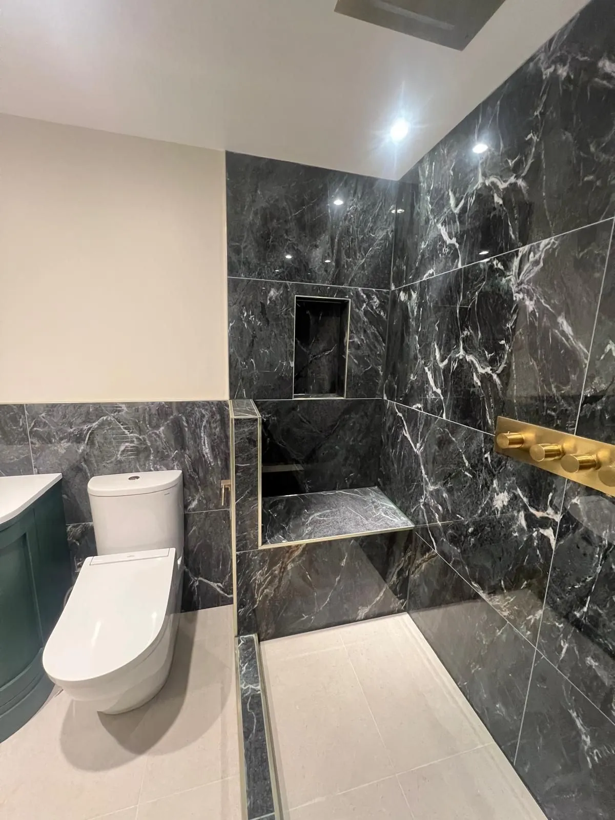 Black marble-effect bathroom with a recessed shower niche and wall-hung toilet