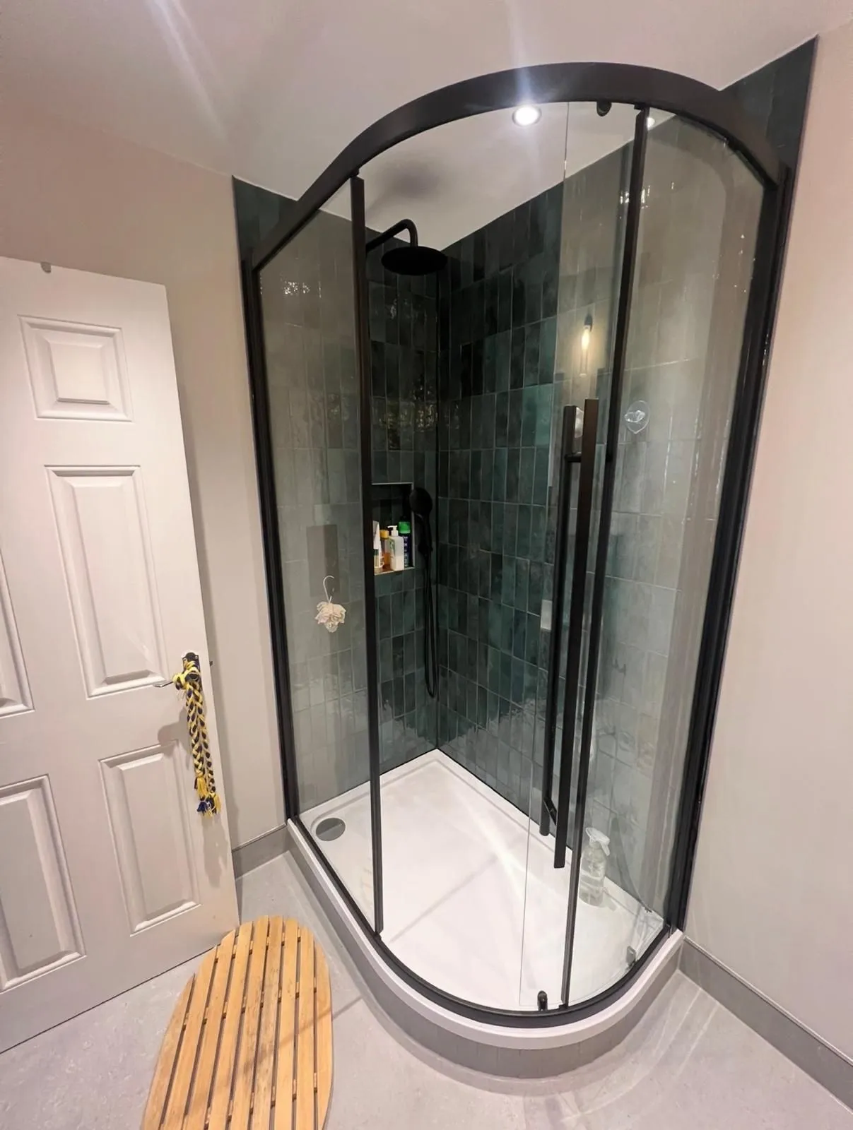 Black-framed quadrant shower with green tiles inside