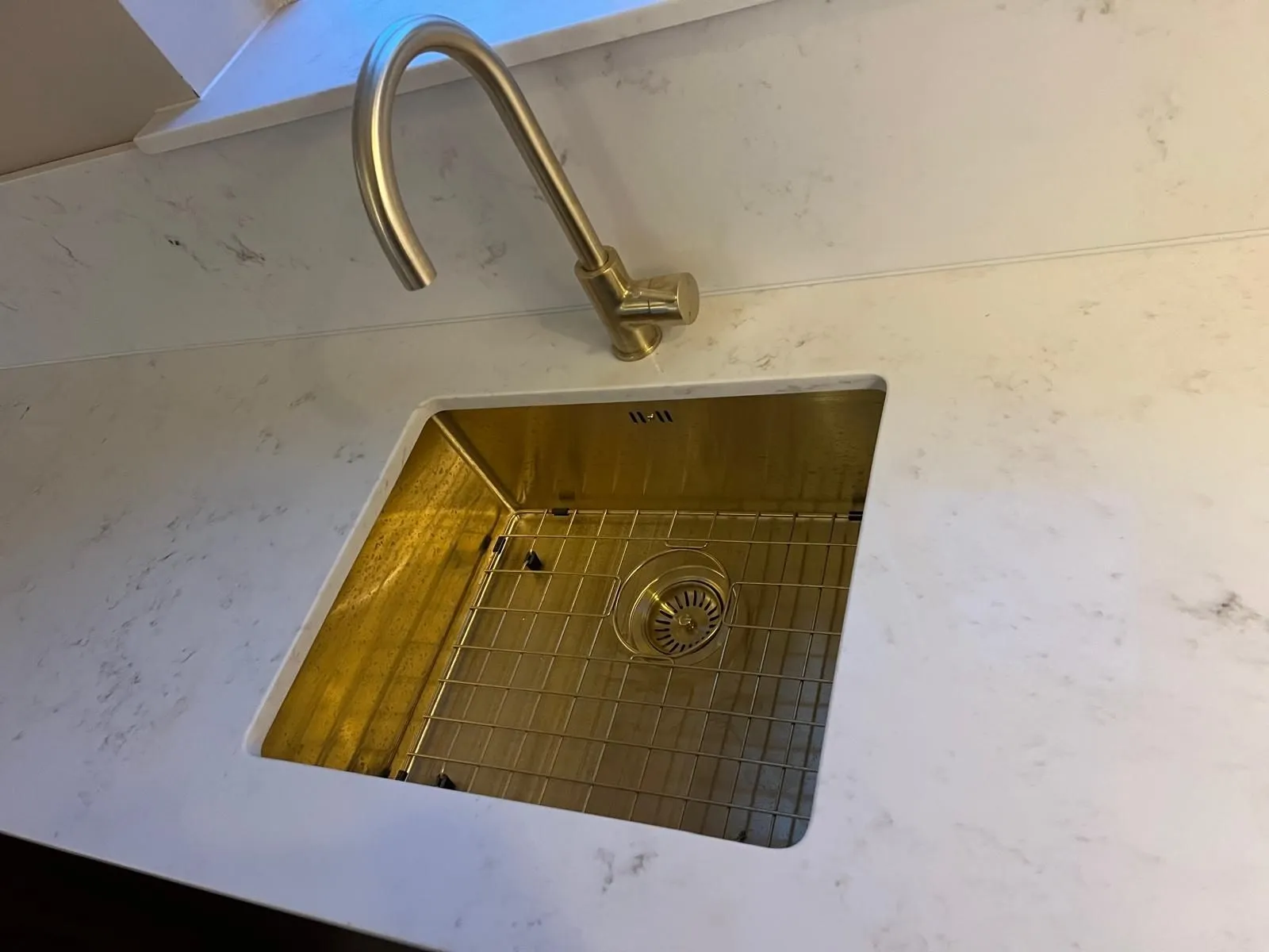 Brushed brass undermount sink and tap set into a white quartz worktop
