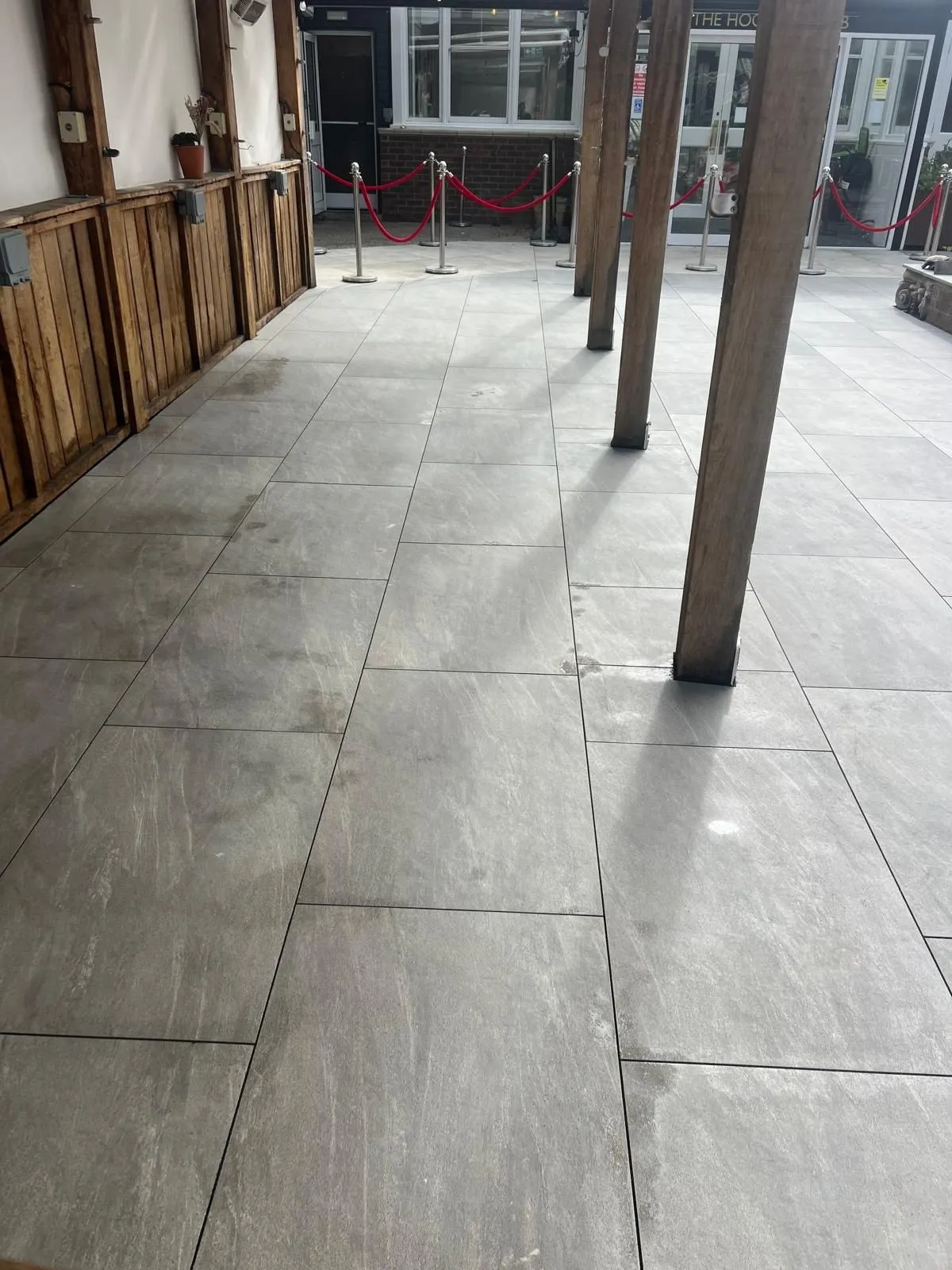 Covered outdoor seating area laid with large grey porcelain slabs