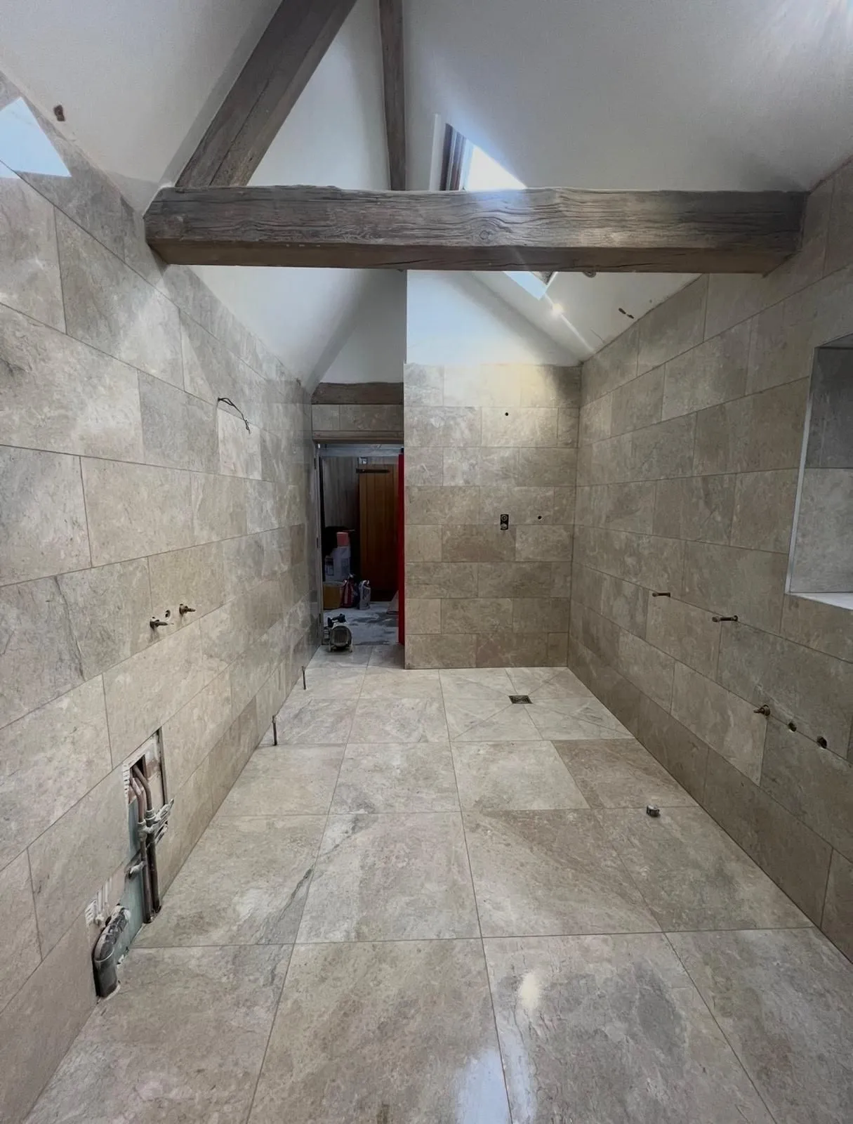 Travertine-effect wet room under exposed roof beams